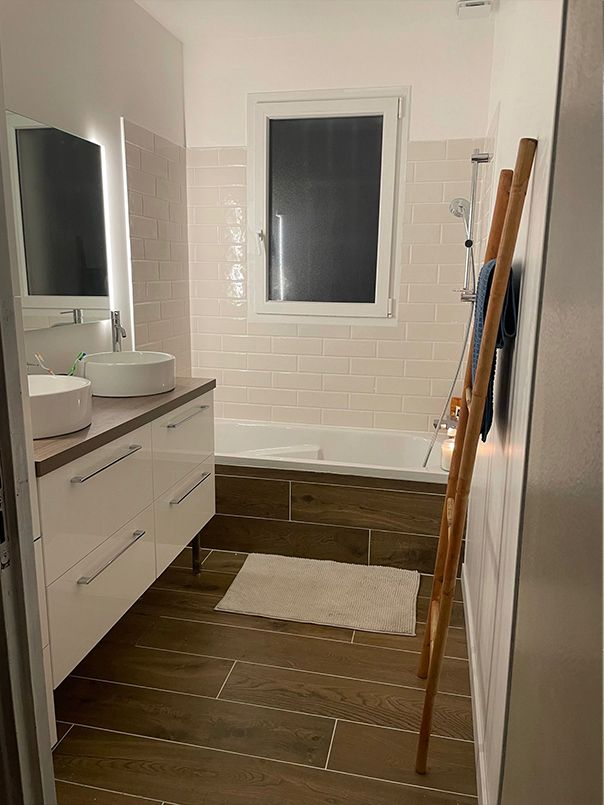 Salle de bain rénovée : double vasque, faïence blanche et sol effet bois